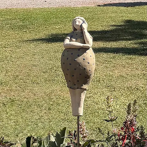 Keramikfigur in grün gepunktetem Kleid, Rückansicht vor Rasen