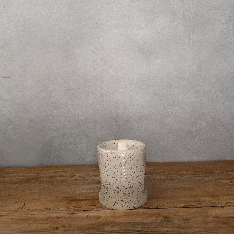 Duftlampe Keramik handgemacht in weißem Steinzeug mit feinen Spots auf Holzoberfläche.